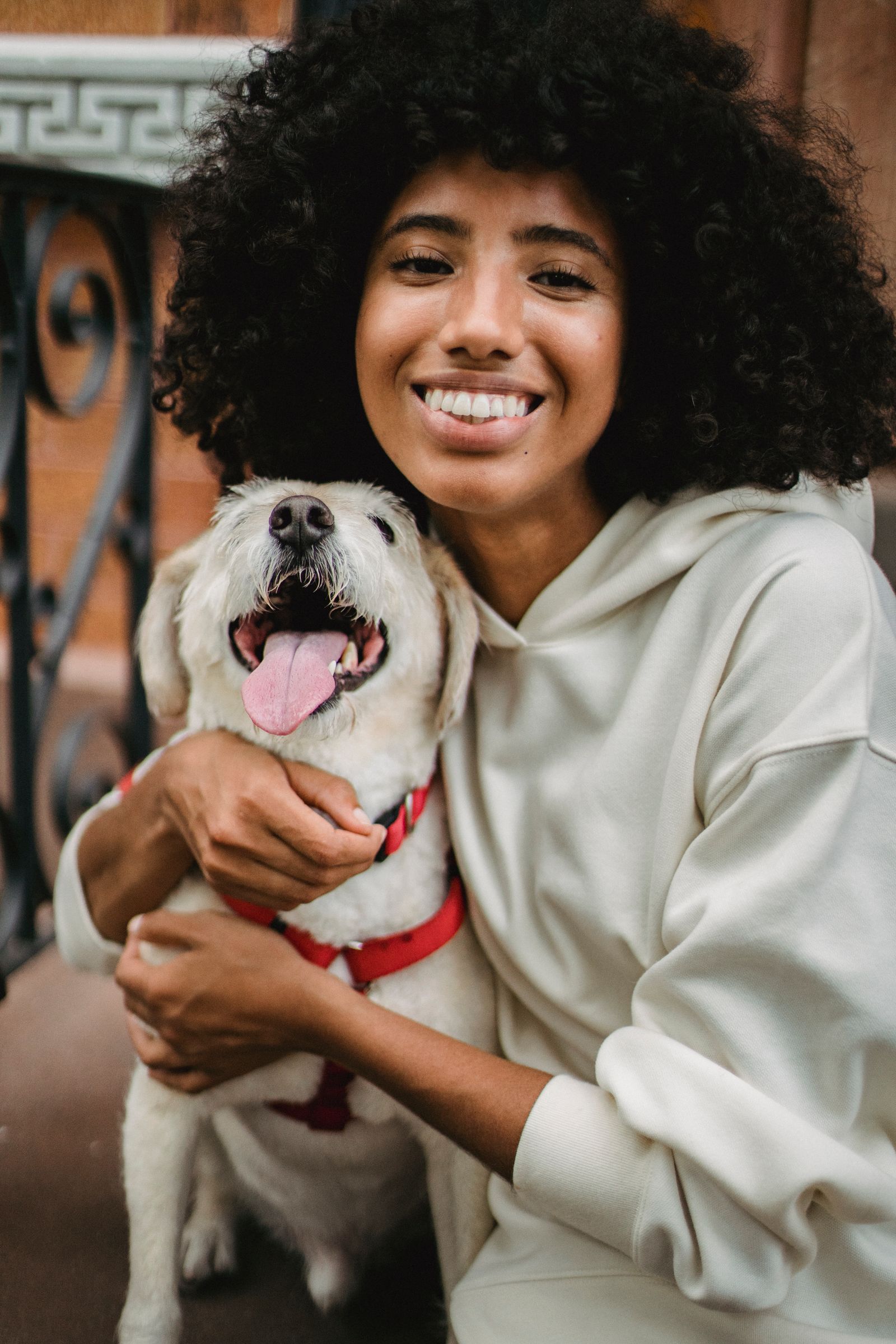 A woman laughing with her arms around her dog on a doorstep